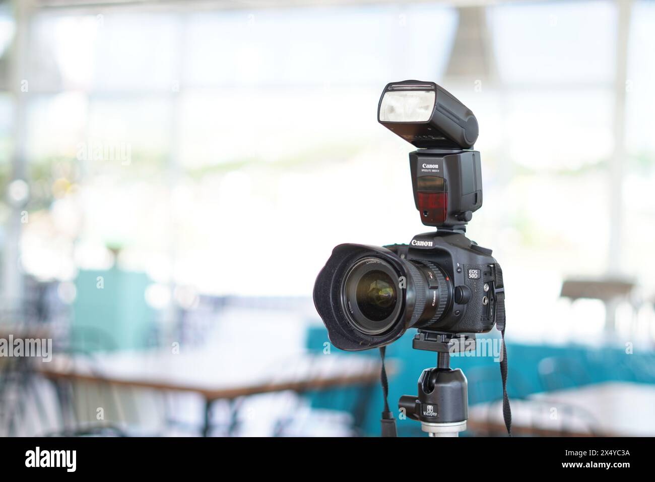 Fotocamera DSLR Canon nera montata su un cavalletto con flash esterno pronto all'uso Foto Stock