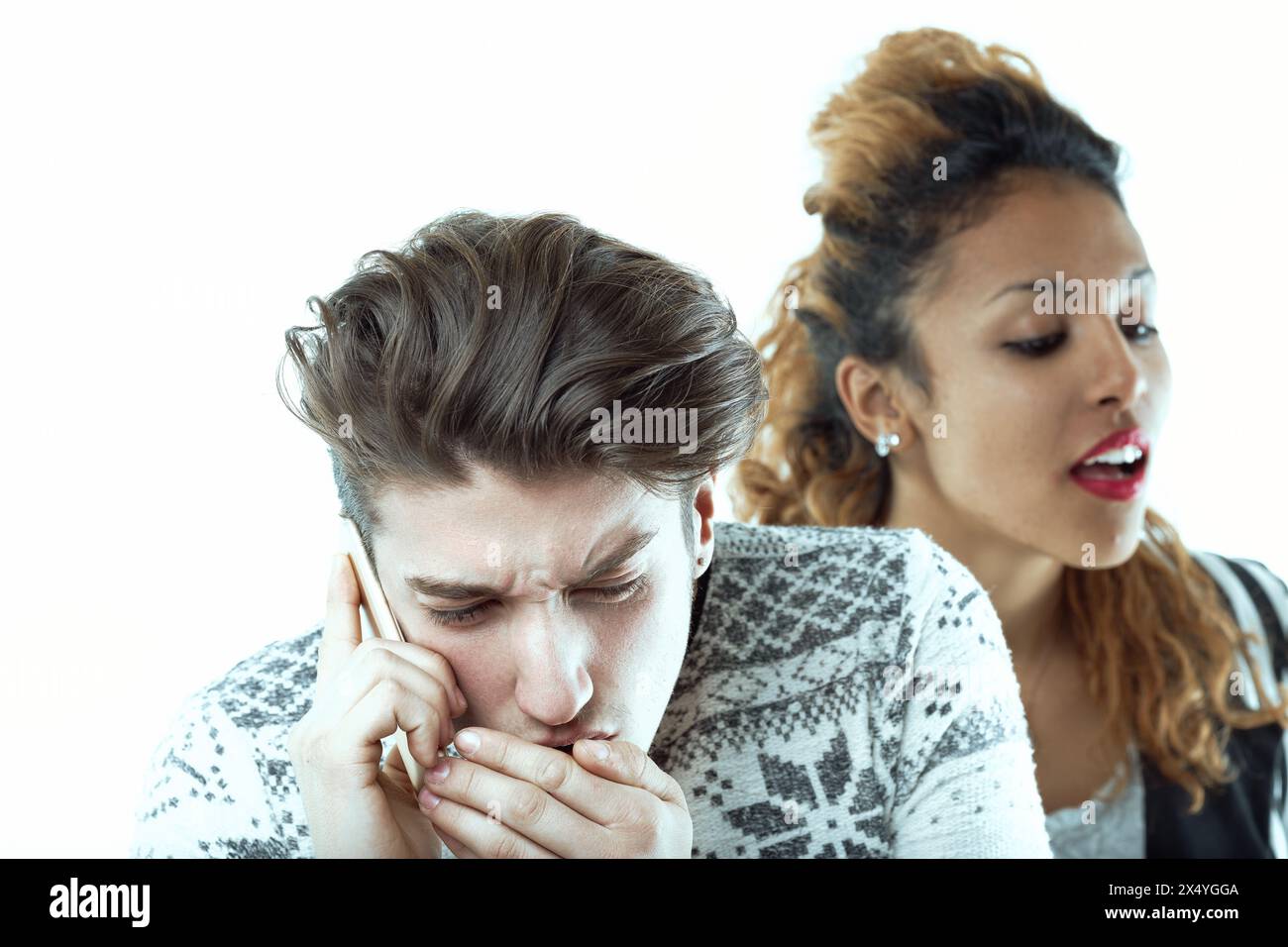 L'uomo lotta visibilmente per mantenere la privacy durante una chiamata mentre una donna dietro di lui ascolta attivamente, trascurando il suo disagio Foto Stock
