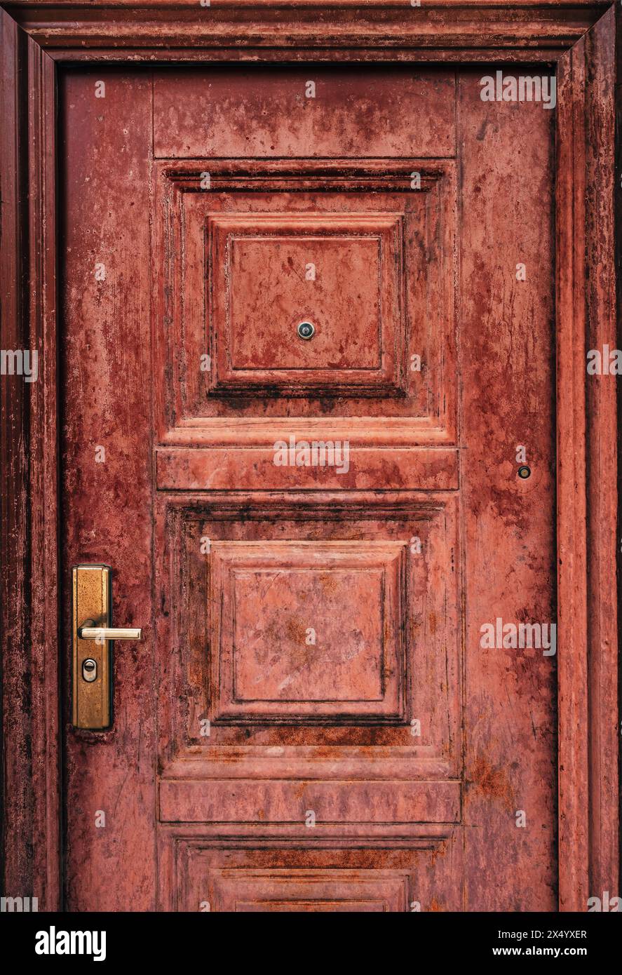 Porta dell'appartamento usurata con maniglia e spioncino danneggiati, immagine verticale Foto Stock