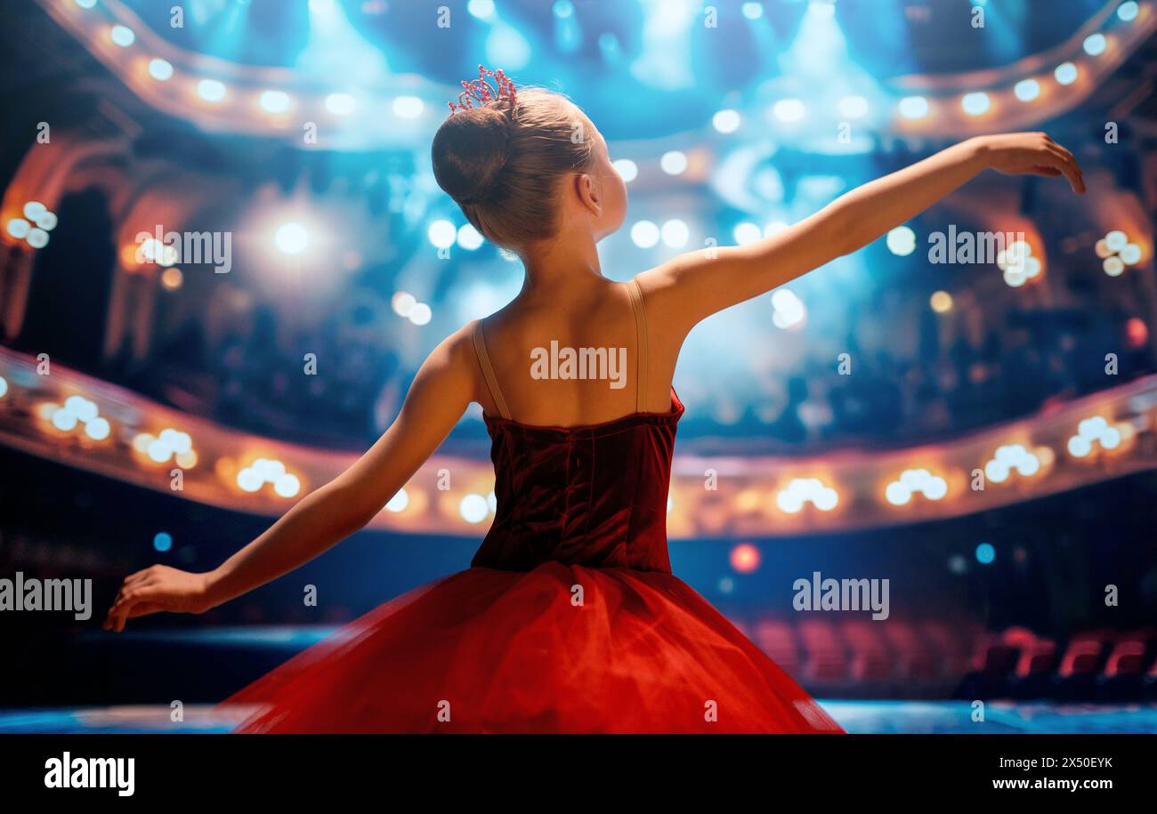 Una bambina carina che sogna di diventare una ballerina. Bambina in un tutu rosso che danza sul palco. Foto Stock