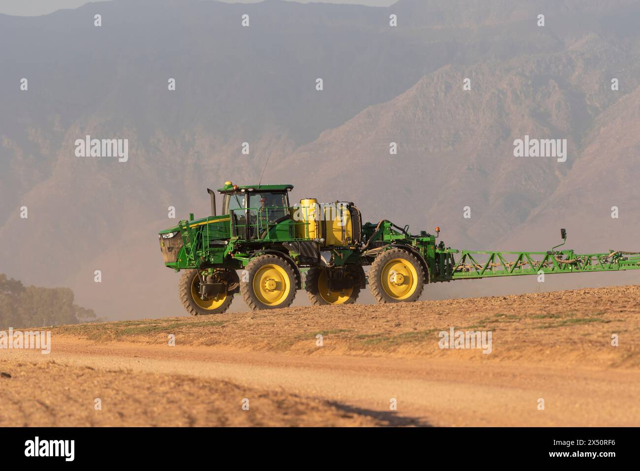 Cape Occidentale, Sudafrica. 24 aprile 2024. Trattore con bracci di irrorazione estesi spruzzando acqua prima che una macchina perforatrice costruisca semi di Canola su fa Foto Stock