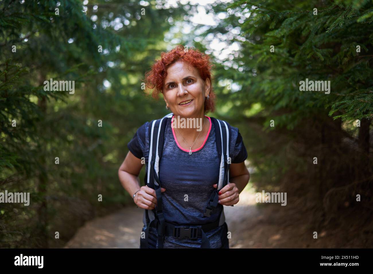 Donna con zaino che cammina su un sentiero nella pineta su una montagna Foto Stock