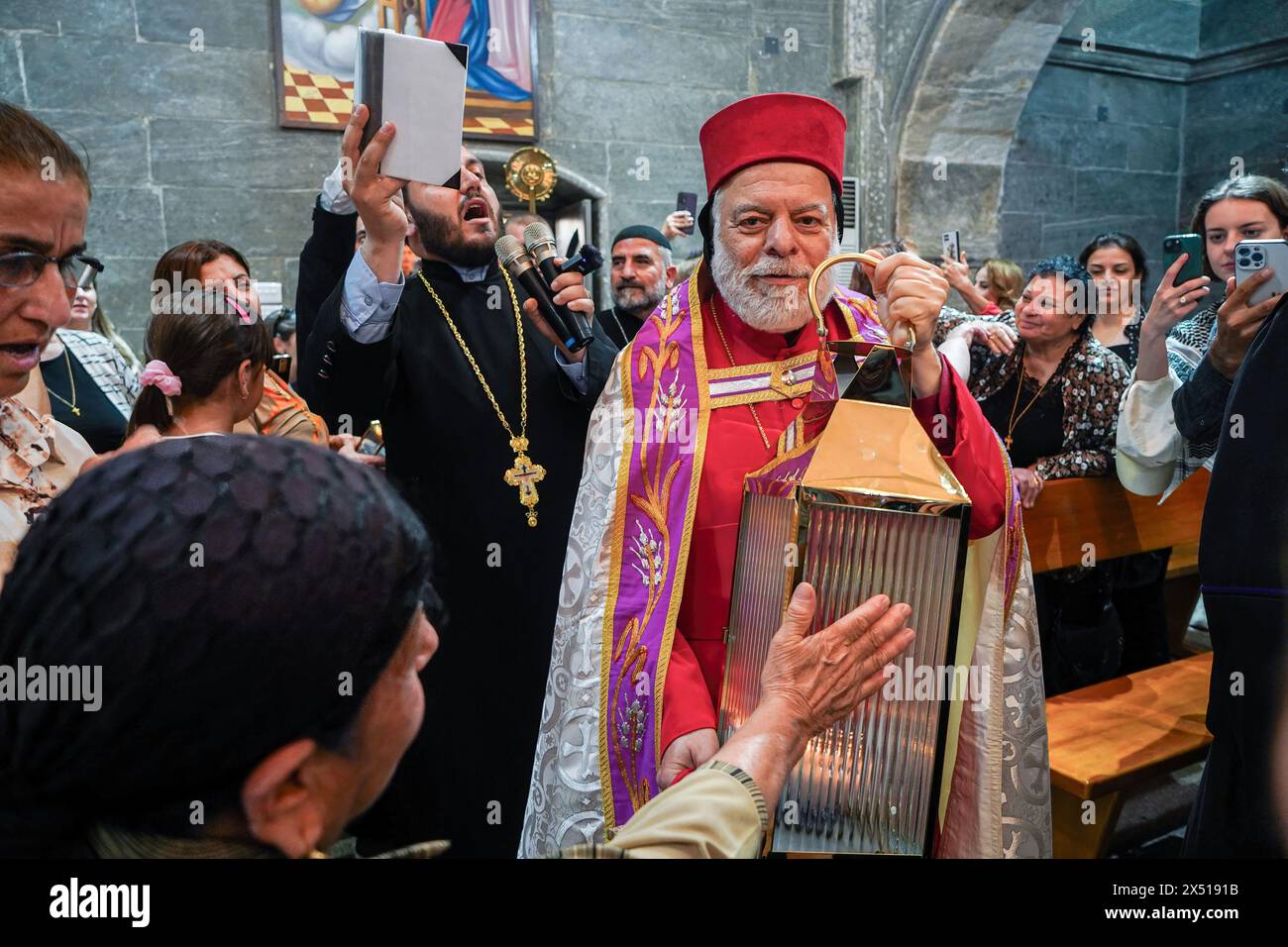 Ninive, Iraq. 5 maggio 2024. La donna cristiana ortodossa siriaca tocca la luce Santa durante la cerimonia del suo arrivo al monastero di Mar Matti vicino a Mosul. I cristiani ortodossi orientali credono che la "luce Santa" emana dall'interno della Tomba di Cristo all'interno della Chiesa del Santo Sepolcro il sabato Santo di Gerusalemme. I credenti cristiani ortodossi orientali celebrano la settimana Santa di Pasqua nella celebrazione della crocifissione e della risurrezione di Gesù Cristo. Il mondo ortodosso orientale celebra il giorno di Pasqua secondo il vecchio calendario Giuliano. Credito: SOPA Images Limited/Alamy Live News Foto Stock