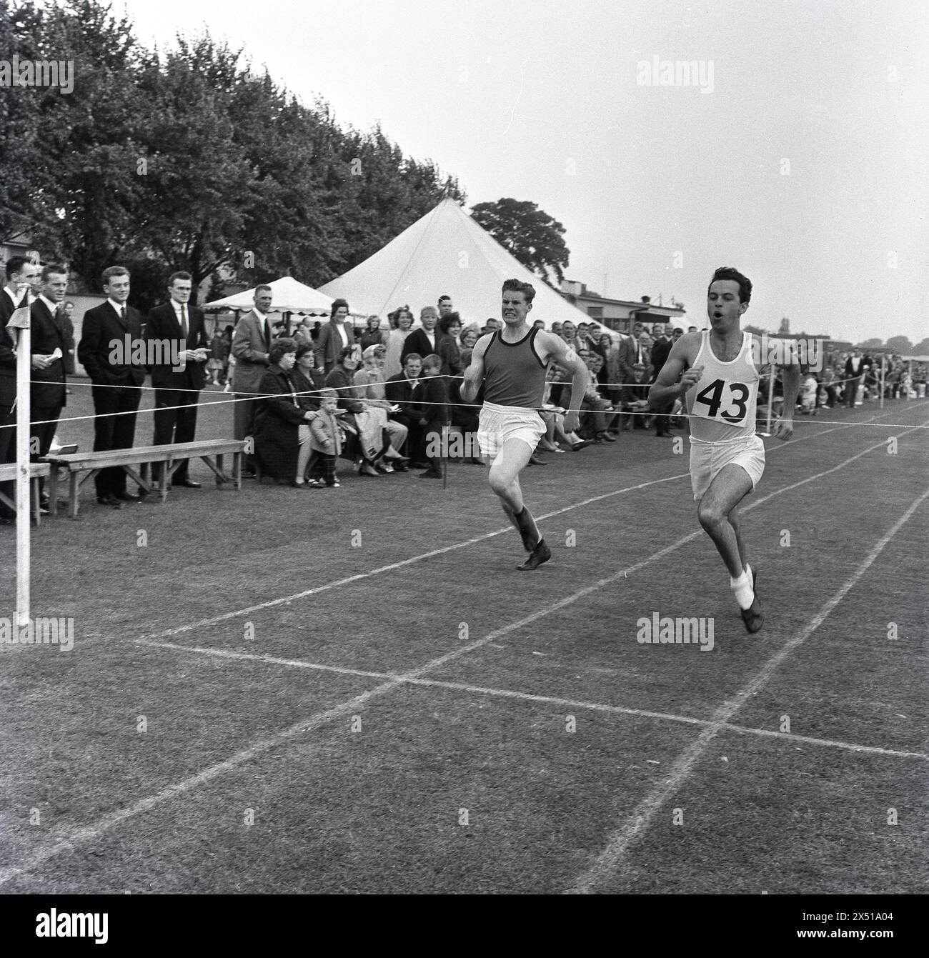 Anni '1960, storici, all'esterno su una pista da corsa in erba durante una giornata di Combined Services Sports e osservati da spettatori in piedi sul lato, due atleti maschi adulti che gareggiano per il traguardo, Inghilterra, Regno Unito. Foto Stock
