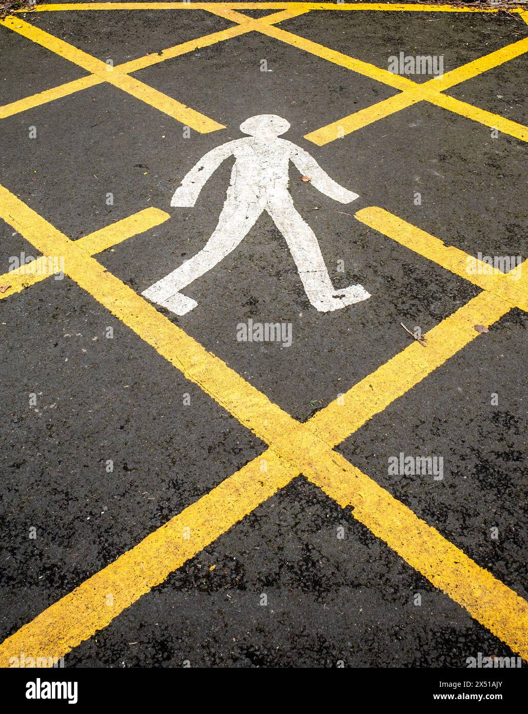 Primo piano di un uomo che cammina dipinto di bianco in una giunzione di scatola gialla su asfalto nero. Foto Stock