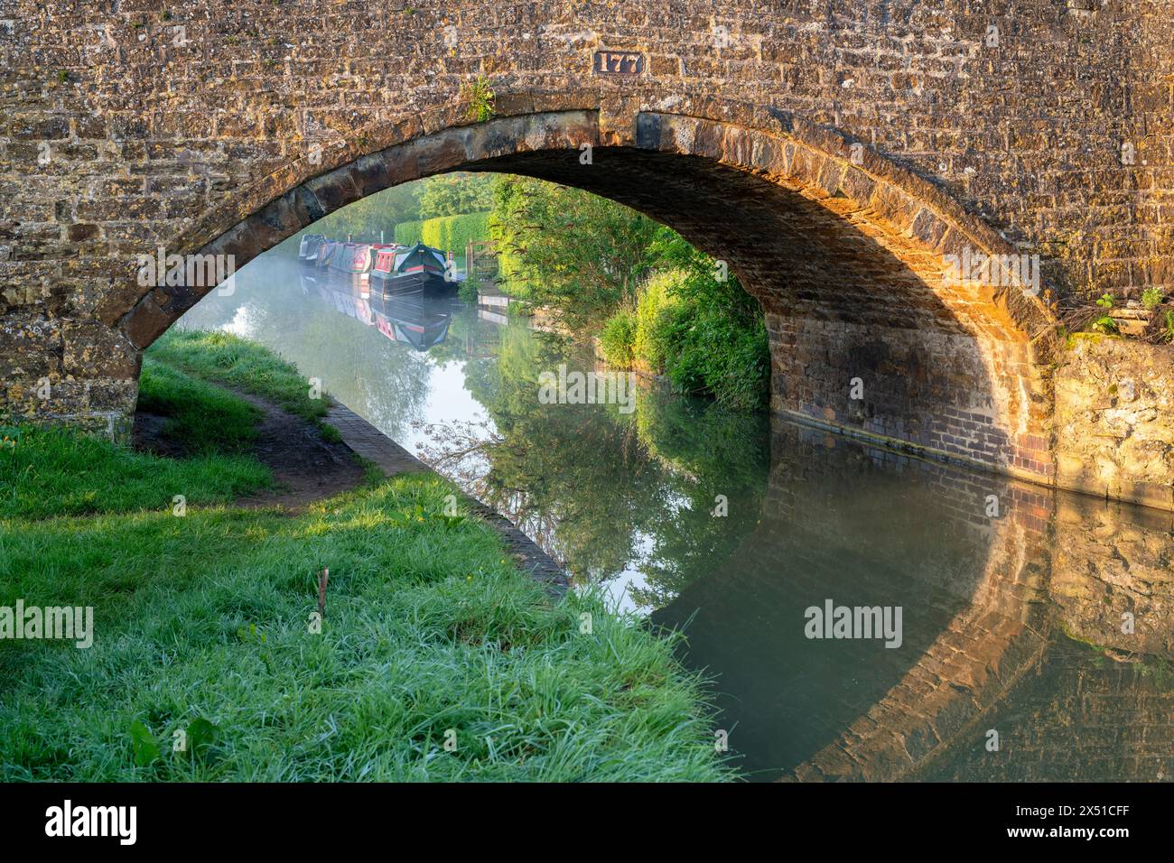 Ponte sul canale e barche a remi lungo il canale di oxford in primavera all'alba. Twyford Wharf, Kings Sutton, Oxfordshire / Northamptonshire Border, Inghilterra Foto Stock