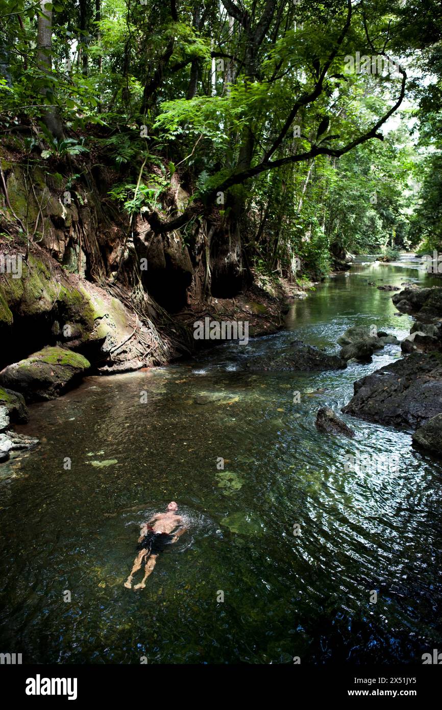 Un nuotatore si rilassa in un fiume nella giungla guatemalteca Foto Stock