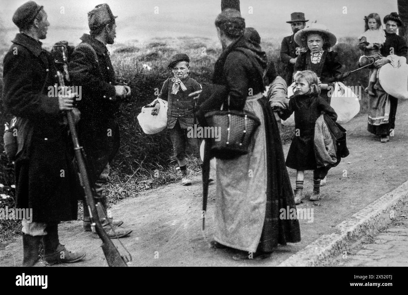 Due fanti belgi della prima guerra mondiale che guardano a famiglie con bambini in fuga dalla loro città a piedi durante l'inizio della prima guerra mondiale nel 1914, Belgio Foto Stock