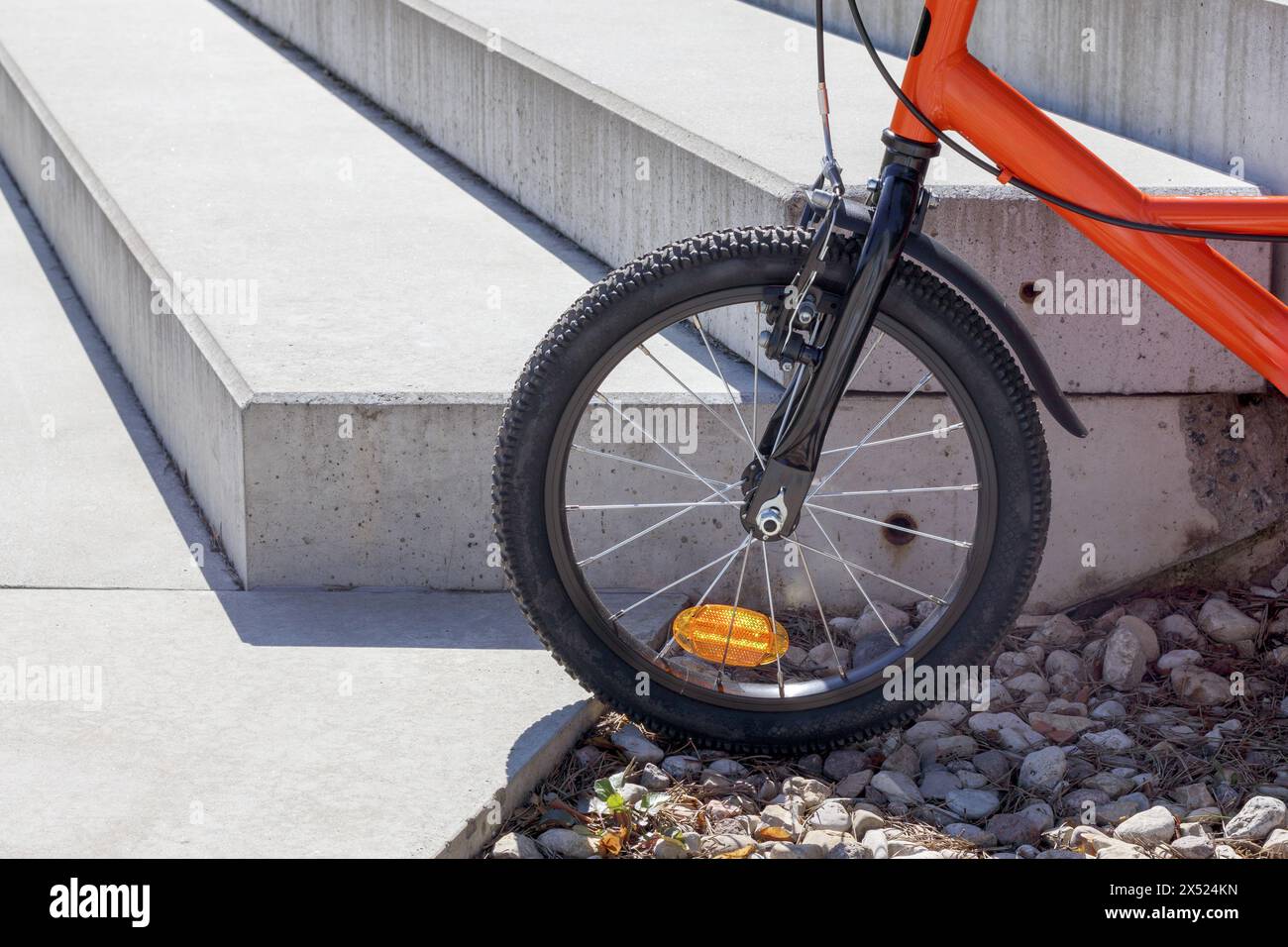 una ruota per biciclette su un telaio rosso di fronte a un edificio Foto Stock