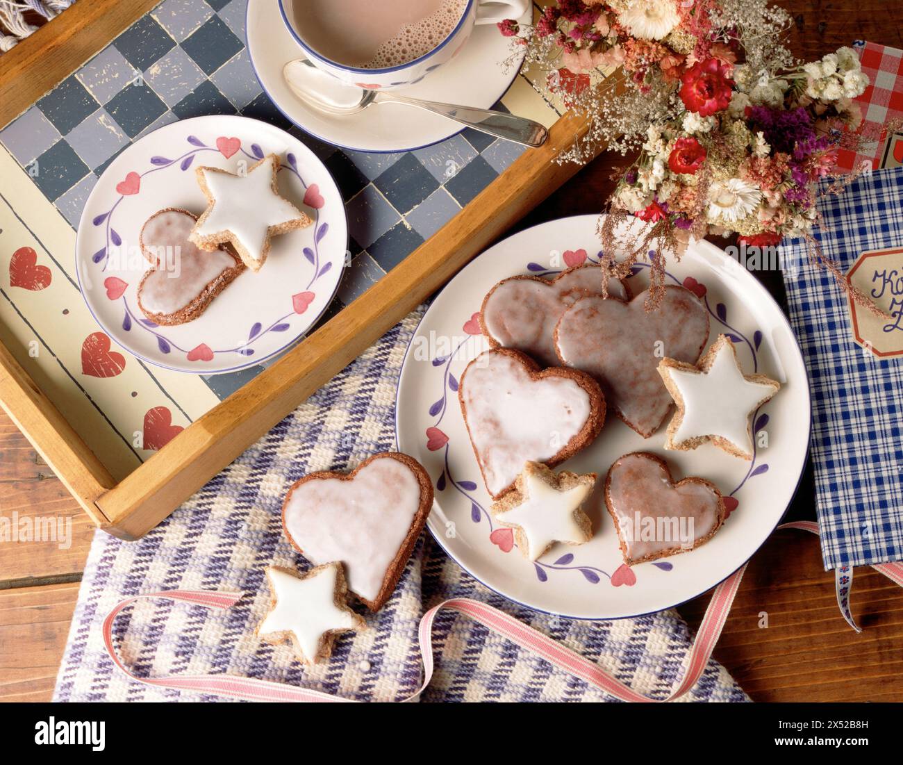 Biscotti fatti in casa a forma di cuore e stella con cioccolata calda su un tavolo rustico. Foto Stock