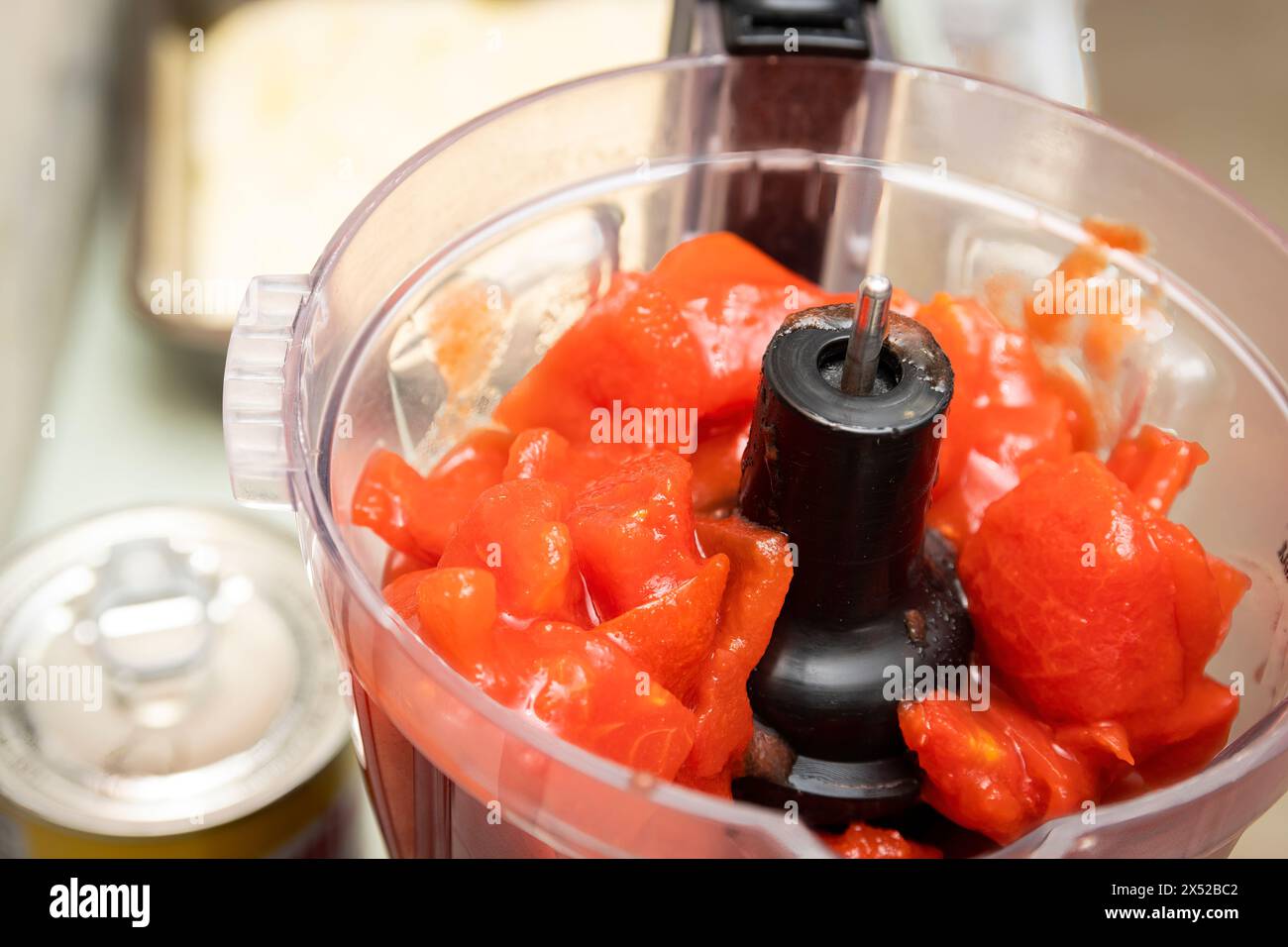 I pomodori tagliati a dadini di lattina sono pronti per essere utilizzati nel robot da cucina, mentre una salsa di pomodoro viene preparata in cucina. Foto Stock