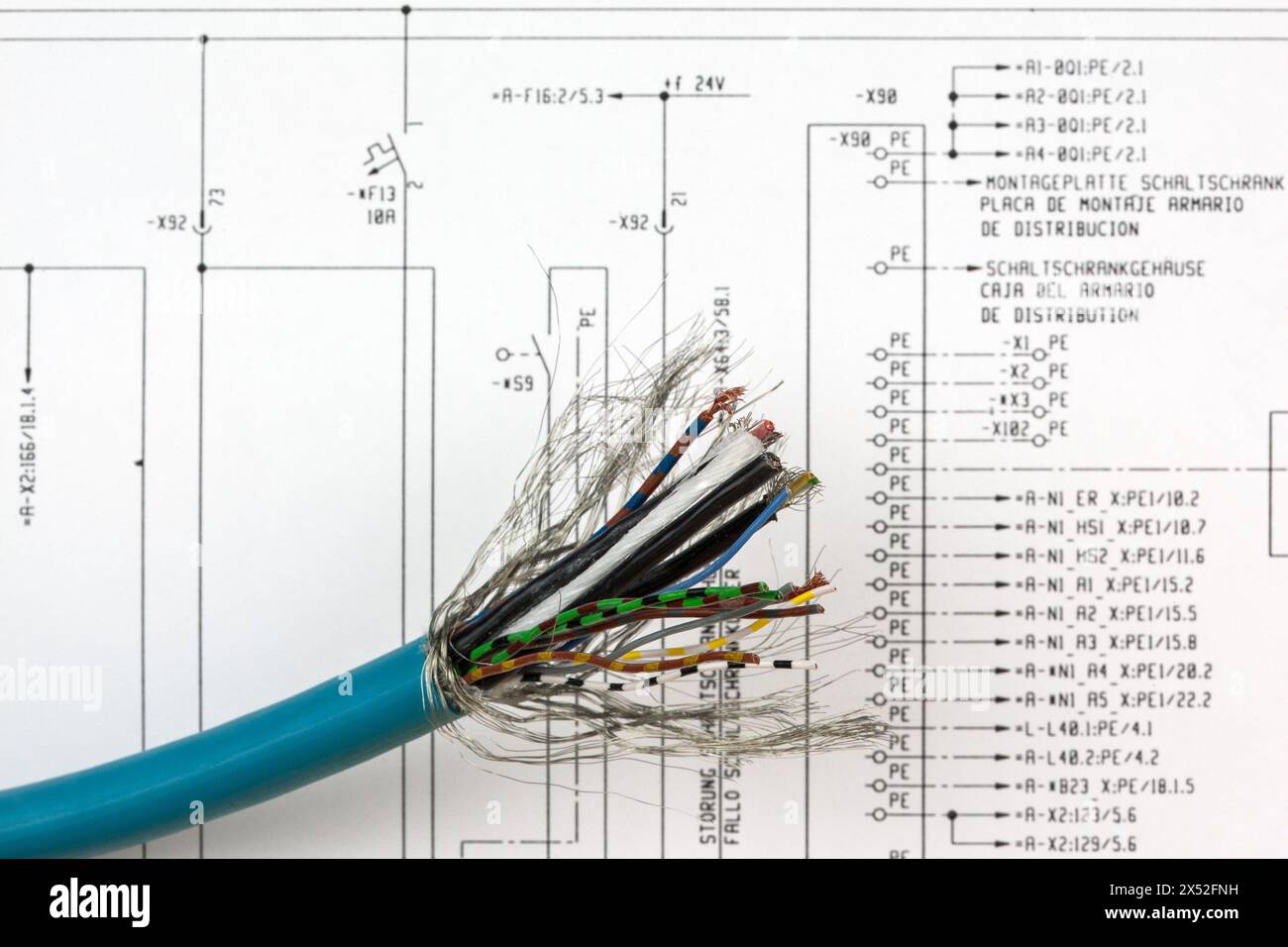 Davanti allo schema elettrico è presente un cavo multiconduttore spelato con fili visibili e codificati a colori pronti per stabilire nuovi collegamenti. Foto Stock