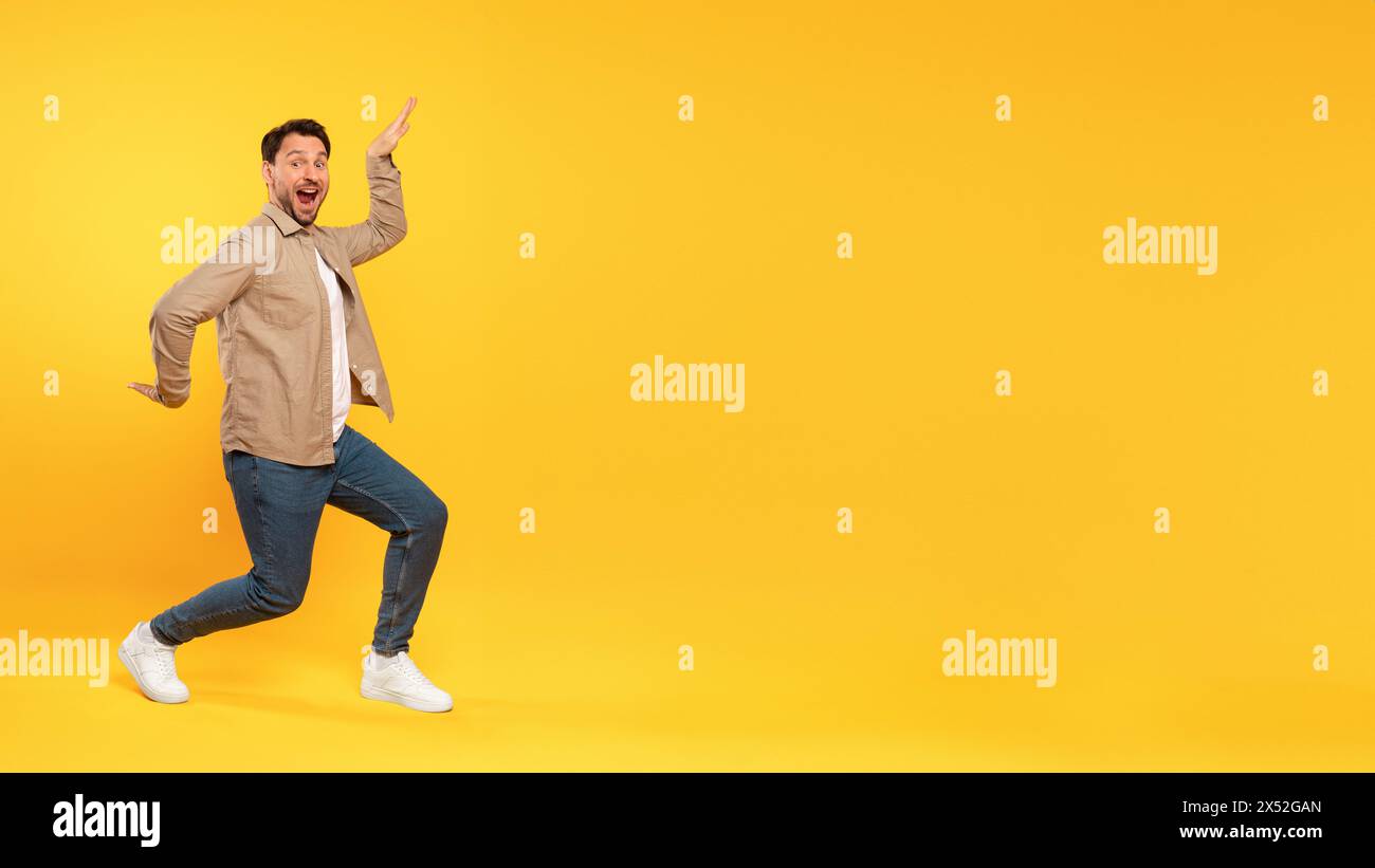 Uomo in giacca Tan che balla su sfondo giallo Foto Stock