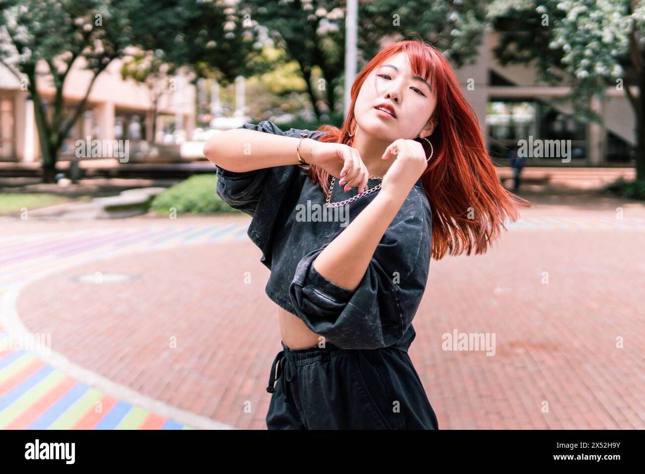 Ballerina coreana dinamica nel mezzo del movimento, abbracciando la vita in una vivace città Foto Stock