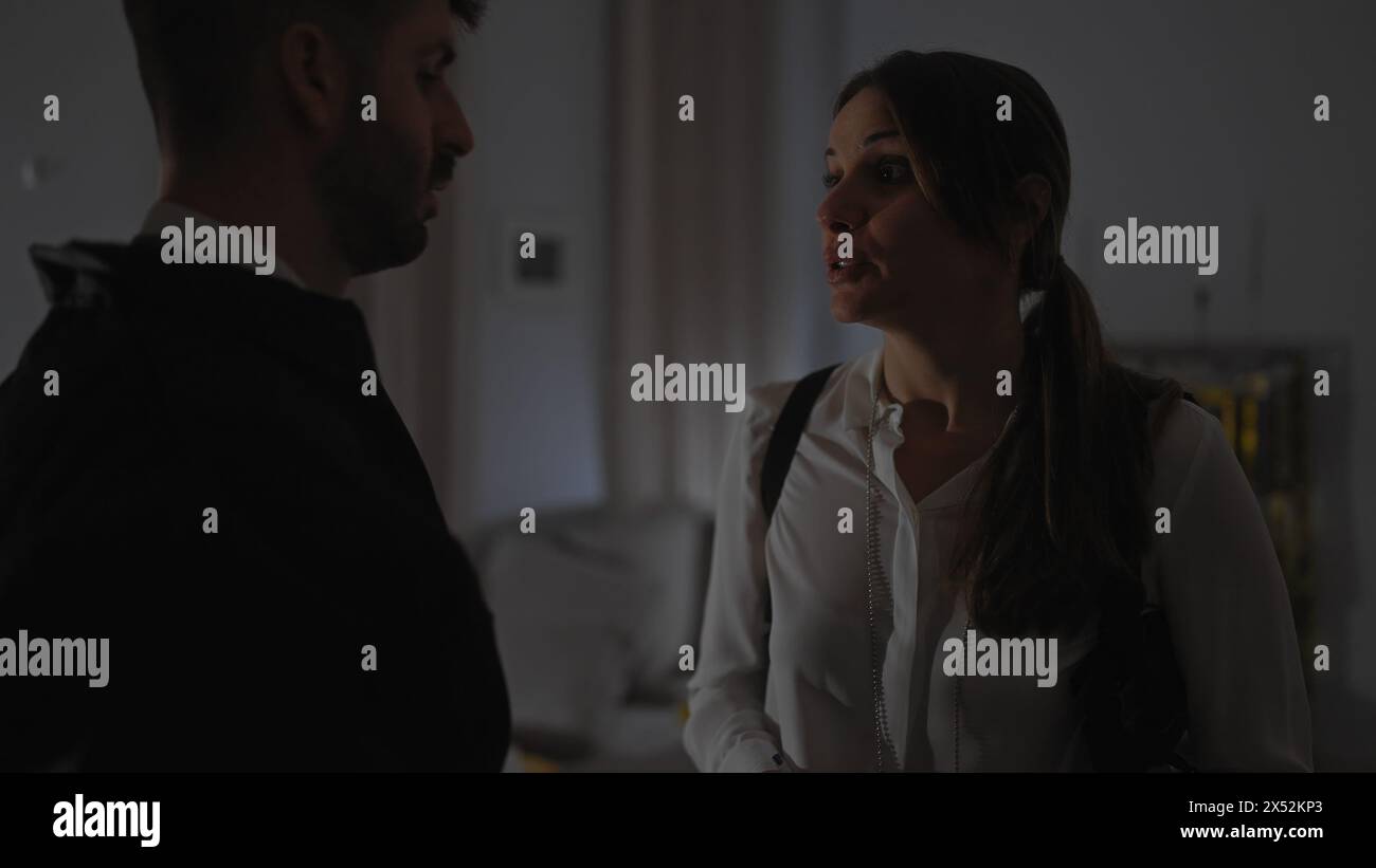 Un uomo e una donna conversano seriamente in casa, implicando uno scenario inquietante e inquietante. Foto Stock