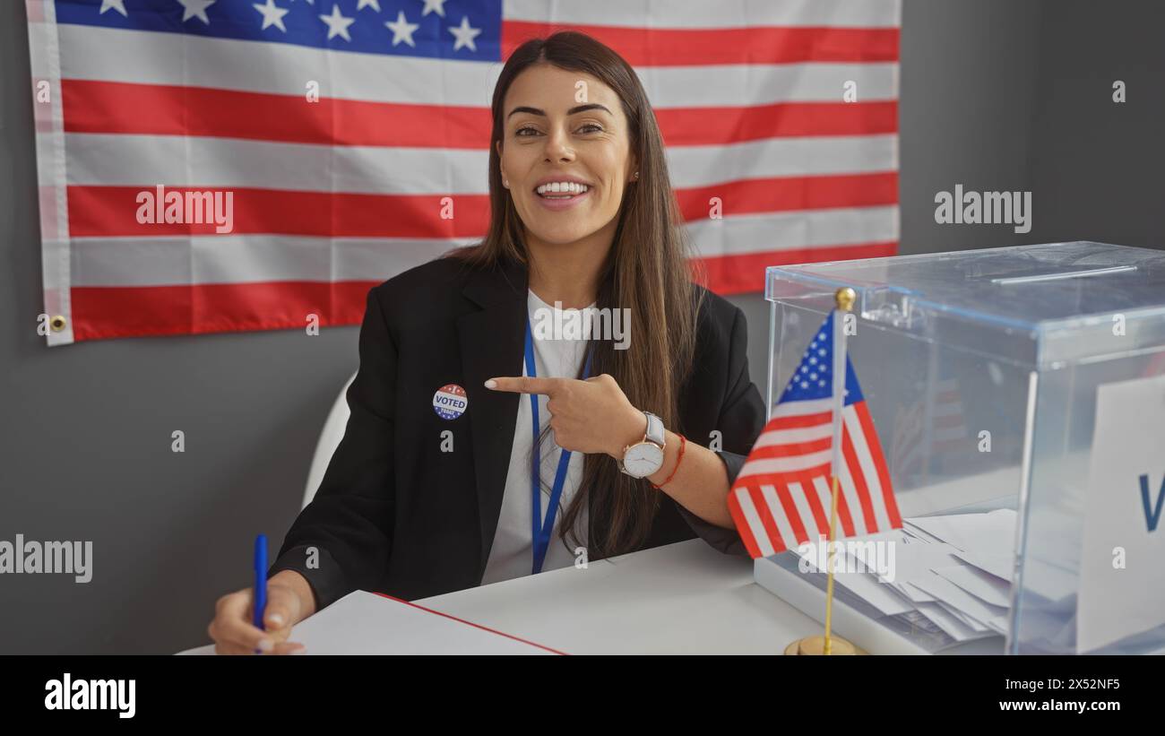 Donna ispanica sorridente con l'adesivo "ho votato" che indica se stessa verso il nostro centro al coperto del college elettorale con bandiera americana. Foto Stock