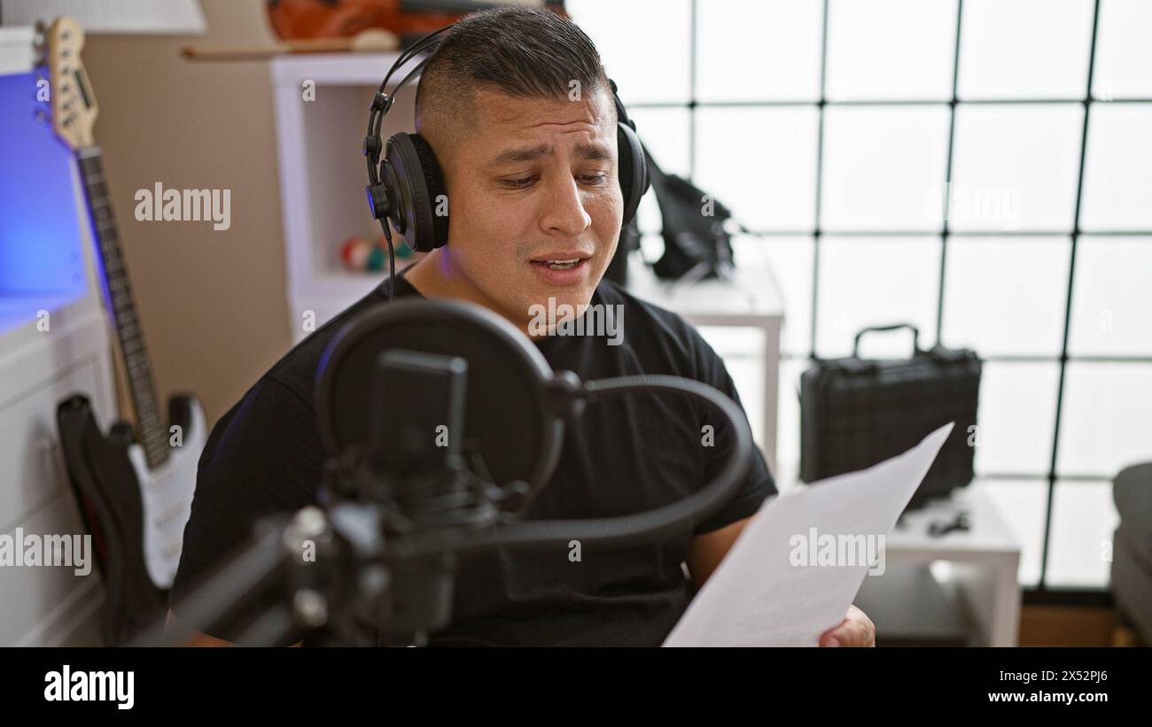 Giovane studioso latino, un musicista energico, serio e concentrato, che canta con passione da uno spartito musicale nel suo vivace studio musicale, immerso in Foto Stock