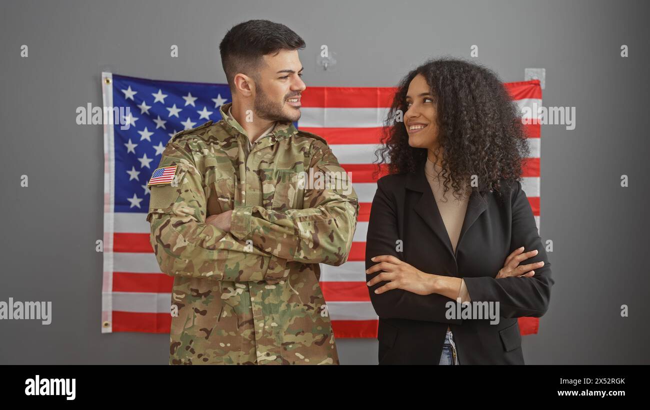 Un uomo sorridente in uniforme militare e una donna d'affari con una bandiera americana sullo sfondo rappresentano unità e professionalità. Foto Stock