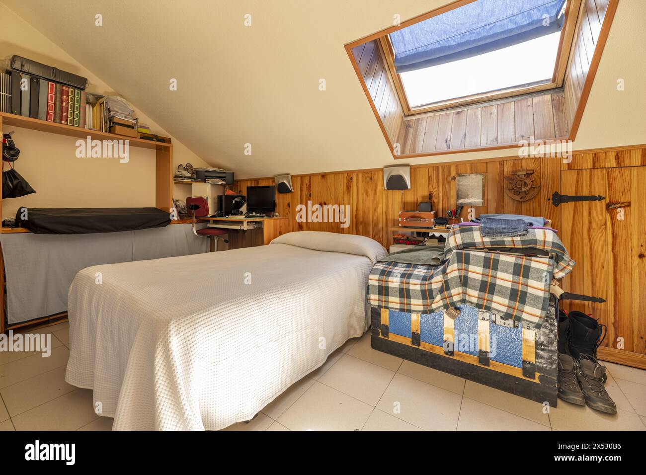 camera da letto attico con lucernario sul soffitto e pareti in legno con linguetta e scanalatura Foto Stock