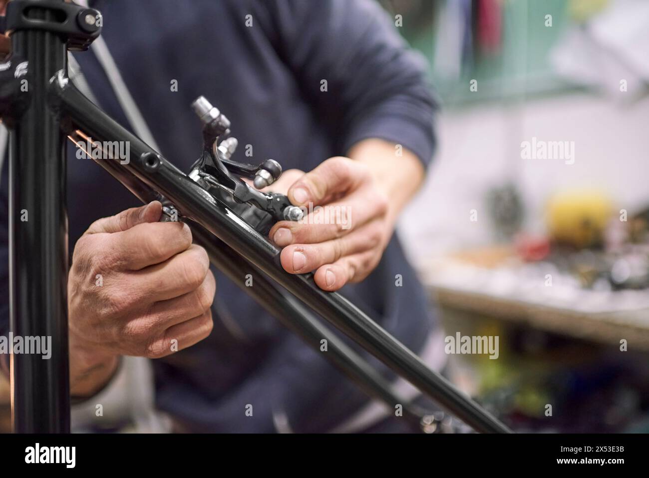 Uomo sconosciuto che assembla l'impianto frenante di una bicicletta come parte del servizio di manutenzione che esegue nella sua officina. Persone vere al lavoro. Foto Stock