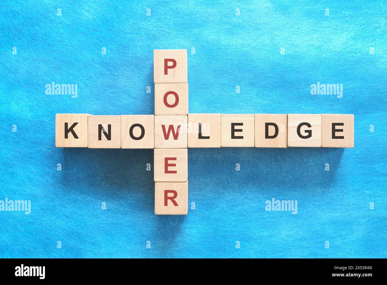 La conoscenza è concetto di potenza. Piatto del puzzle con parole incrociate su sfondo blu. Foto Stock