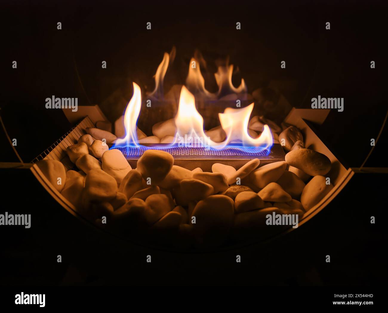 Fiamma in un camino decorativo con pietre bianche e pannelli di vetro Foto Stock