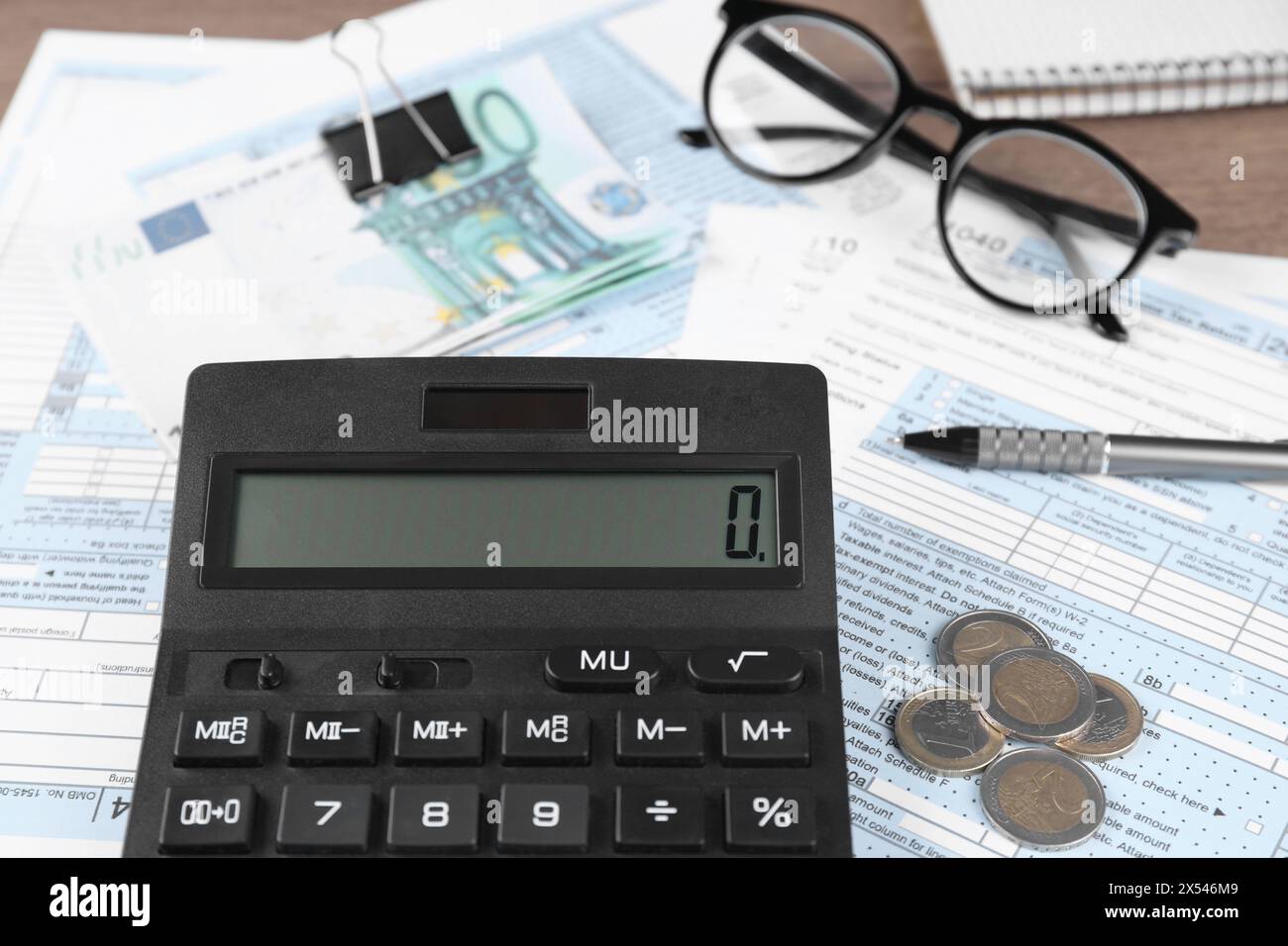 Contabilità fiscale. Calcolatrice, documenti, soldi, occhiali e penna sul tavolo, primo piano Foto Stock