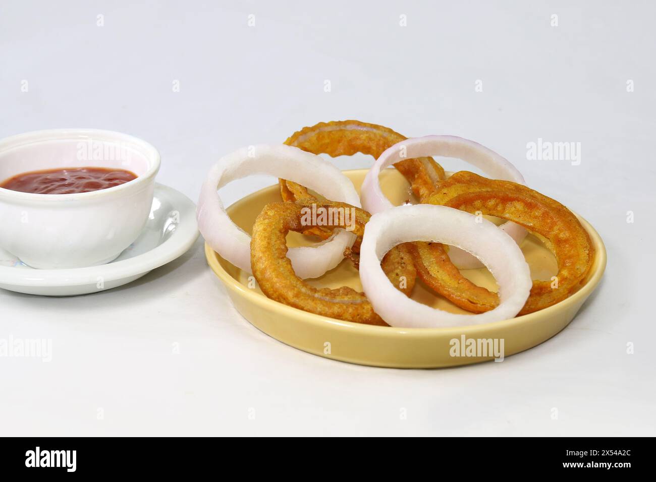 Anelli di cipolla fritti croccanti fatti in casa con salsa di pomodoro e fette di cipolla crude. spuntini serali. Foto Stock