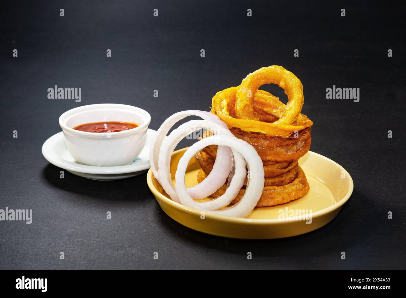 Anelli di cipolla fritti croccanti fatti in casa con salsa di pomodoro e fette di cipolla crude. spuntini serali. Foto Stock