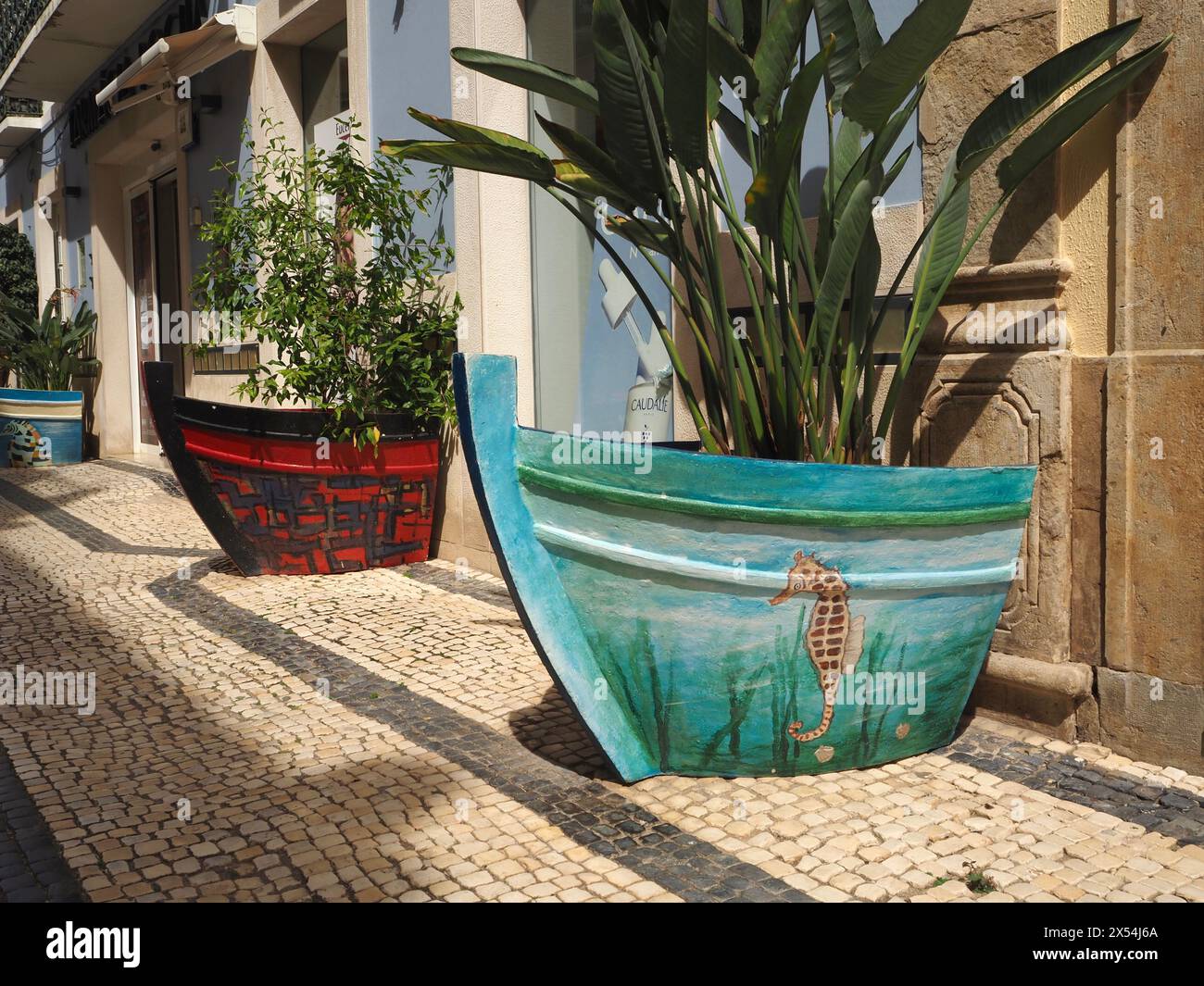 Grandi fioriere decorative dipinte a mano a forma di barca nel centro di Olhão nel sud del Portogallo, che celebrano il forte patrimonio di pesca di questa piccola città Foto Stock