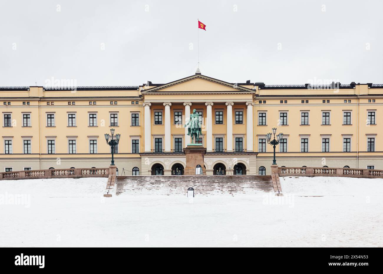 Facciata del palazzo reale neoclassico di Oslo in inverno con volo standard reale norvegese e statua equestre del re Carl Johan, Oslo, Norvegia Foto Stock