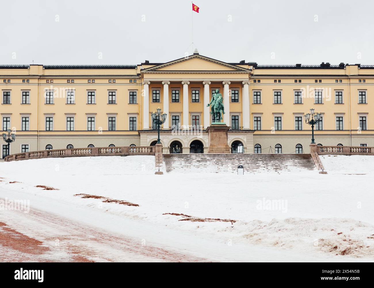 Facciata del palazzo reale neoclassico di Oslo in inverno con volo standard reale norvegese e statua equestre del re Carl Johan, Oslo, Norvegia Foto Stock