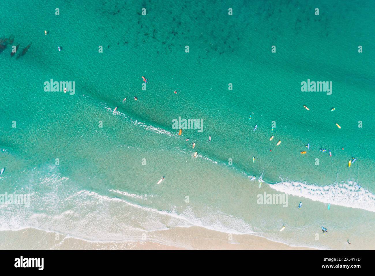 vista aerea zenithal con drone di una spiaggia con persone che imparano a fare surf, concetto di scuola di surf Foto Stock