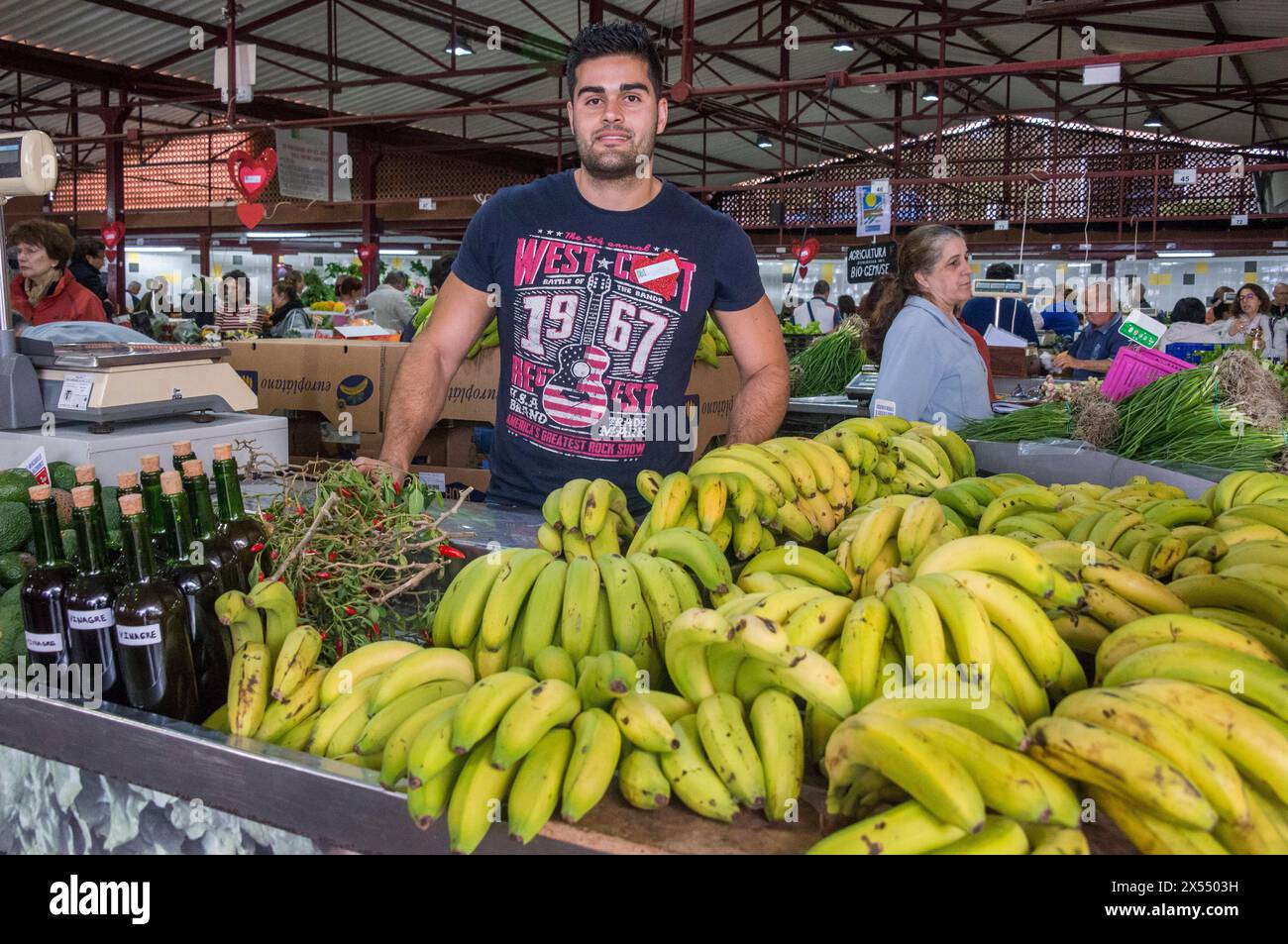 Giovane in una stalla che vende frutta, con banane, in un mercato agricolo nel comune di Tacoronte Foto Stock
