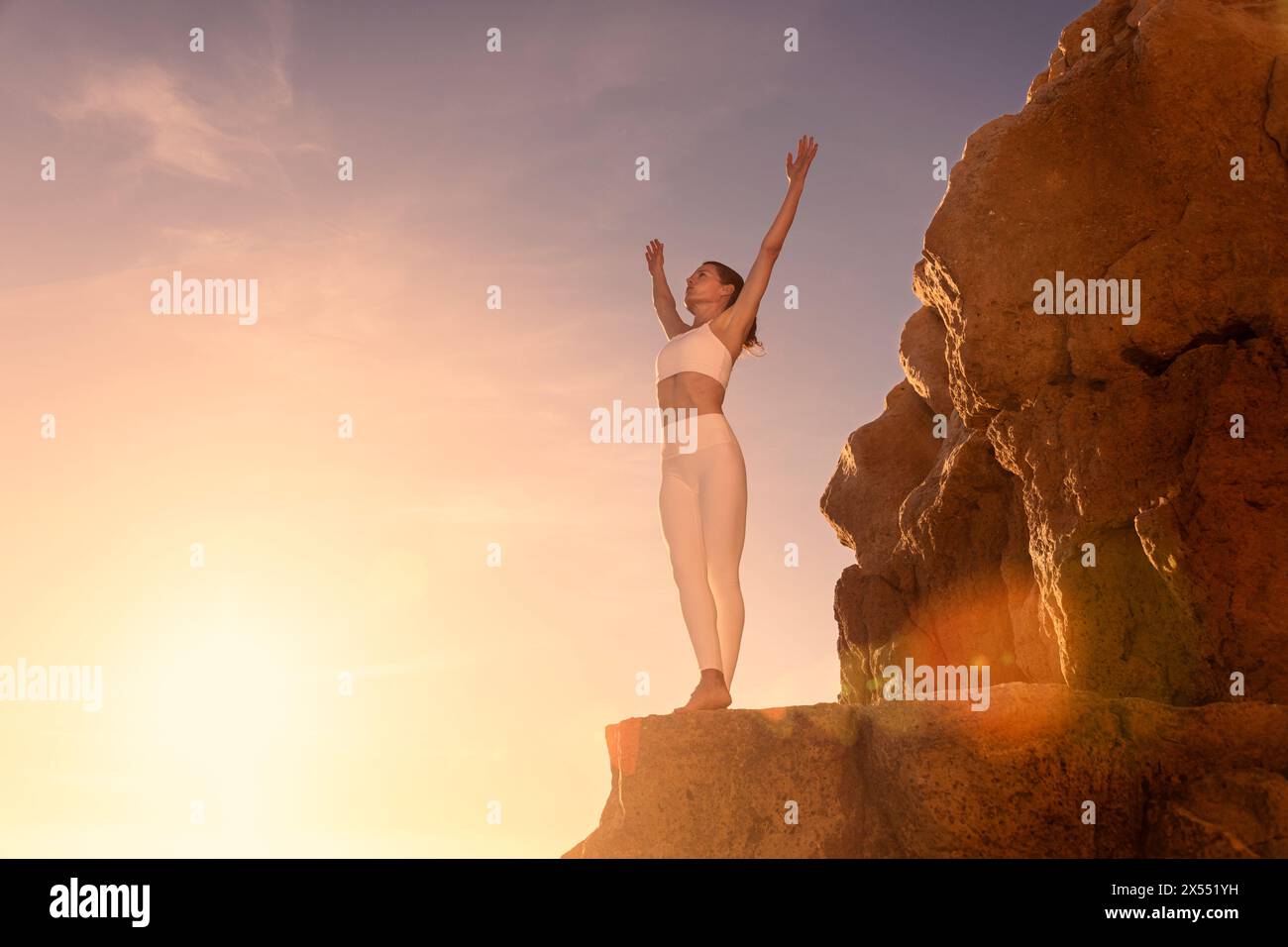 Donna con le braccia spalancate che gode del sole, in piedi sulla roccia con le mani alzate, rilassati o felice o viaggia in libertà. Concetto di successo e vincitore Foto Stock