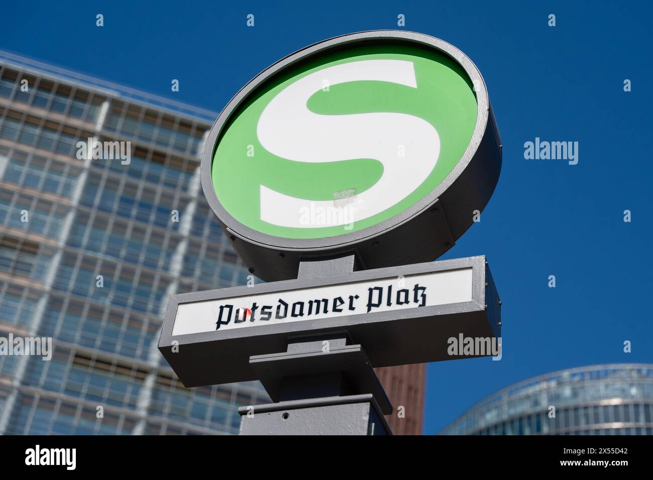 Un segno verde con la lettera S. Il cartello è su un palo vicino a un edificio Foto Stock