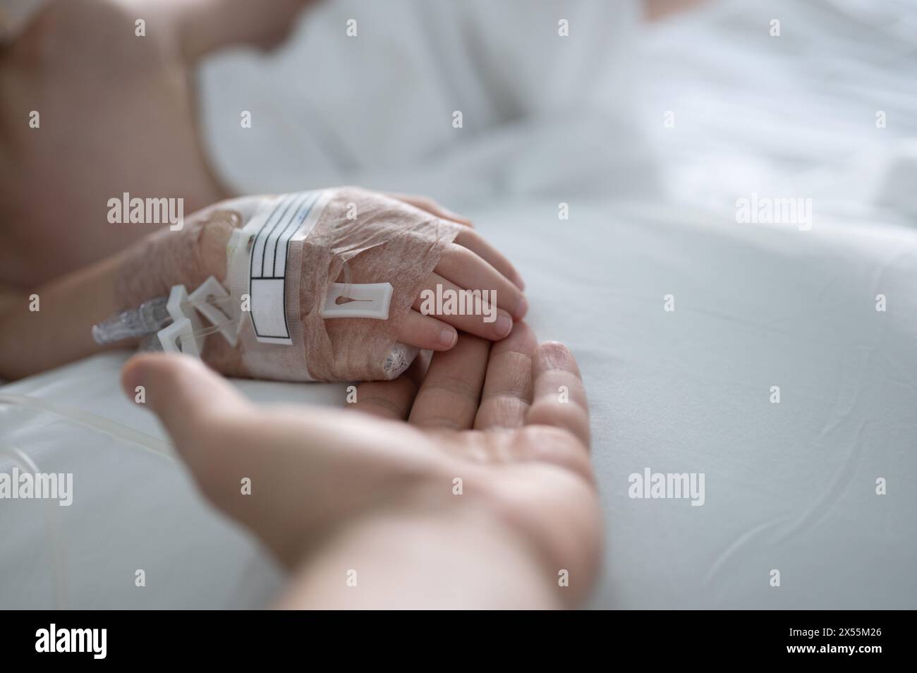 Aiutare il bambino a guarire dopo la malattia in ospedale tenendo la mano con iv Foto Stock