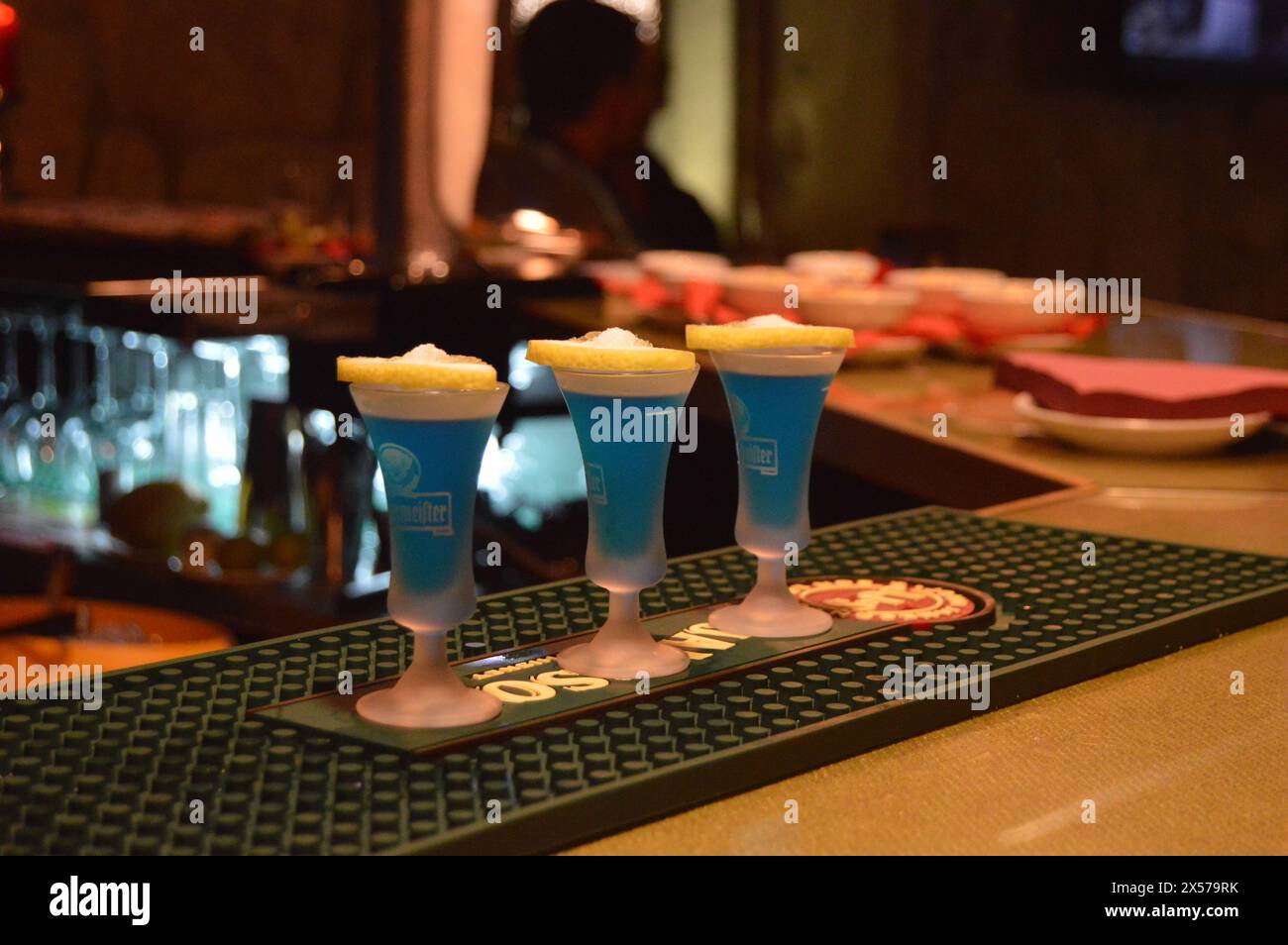 Trio vibrante: 3 shot blu adornati con scorza di limone. Saluti al momento! Foto Stock