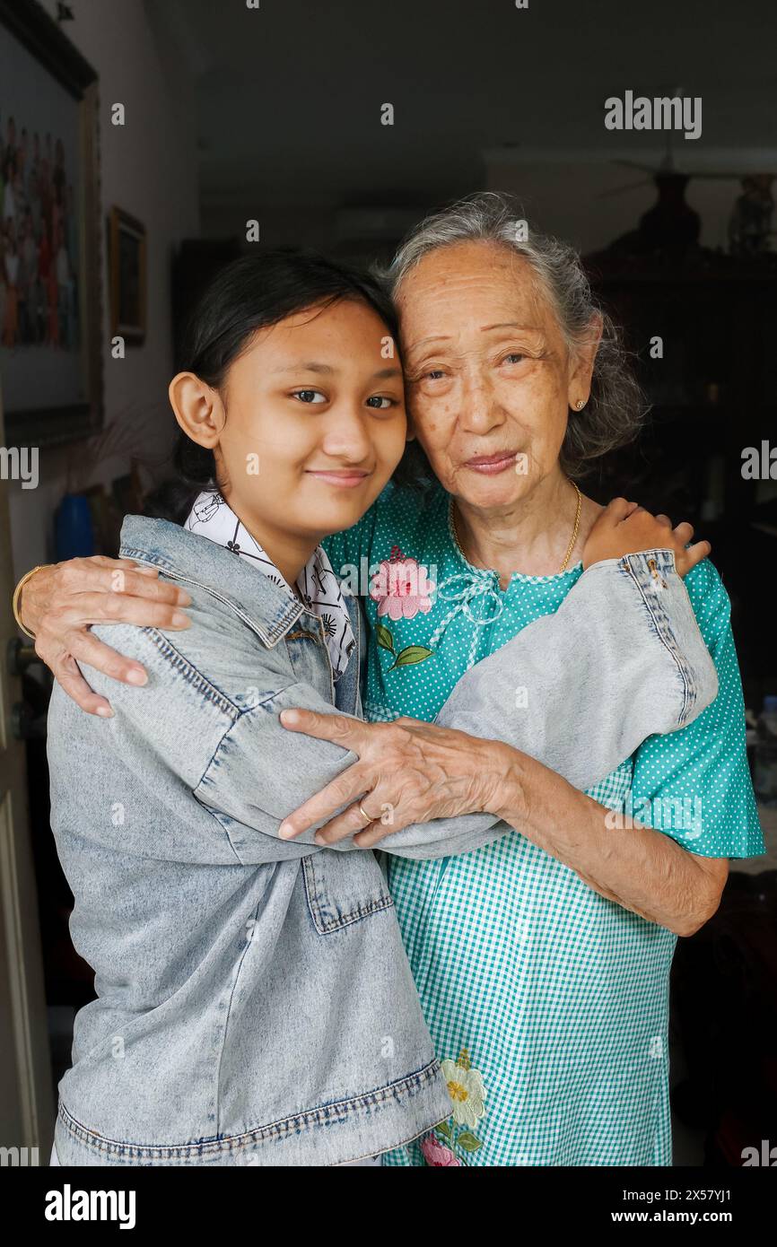 Ritratto della bella nonna e della nipote adolescente che si abbracciano e sorridono felici di vedersi Foto Stock