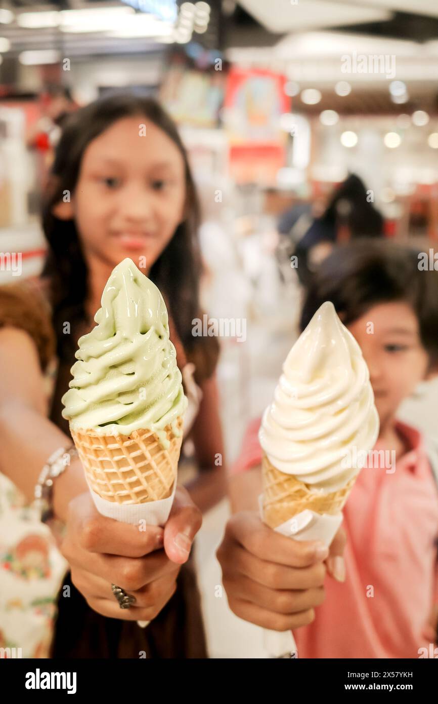 Bambini asiatici, ragazzo e adolescente ragazza che mostra gelato sul cono Foto Stock