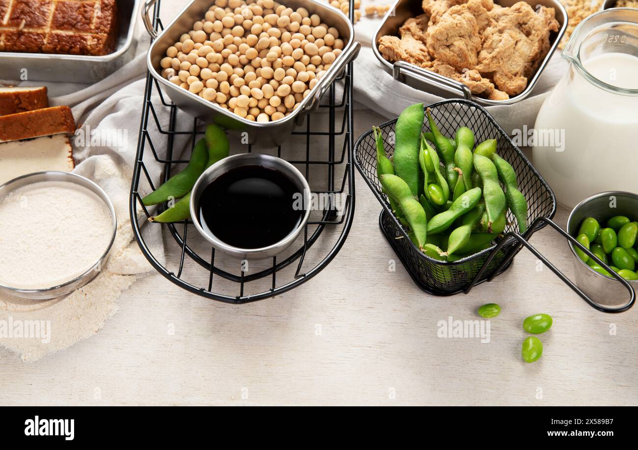 Vari prodotti di soia con semi di soia, tofu, salsa di soia e latte di soia su sfondo chiaro. Vista dall'alto, copia spazio. Foto Stock