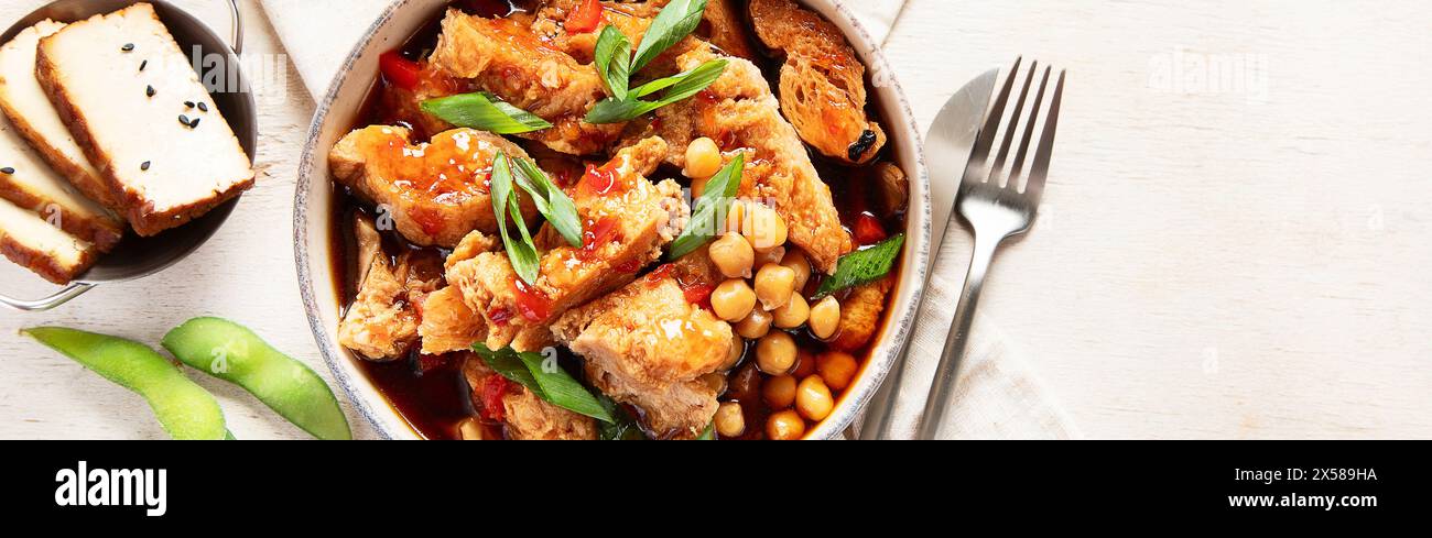Soia con carne di soia, cipolla e tofu su sfondo di legno chiaro. Cibo vegano. Vista dall'alto, copia spazio Foto Stock