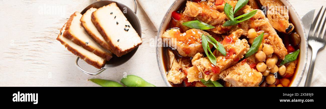 Soia con carne di soia, cipolla e tofu su sfondo di legno chiaro. Cibo vegano. Vista dall'alto, copia spazio Foto Stock