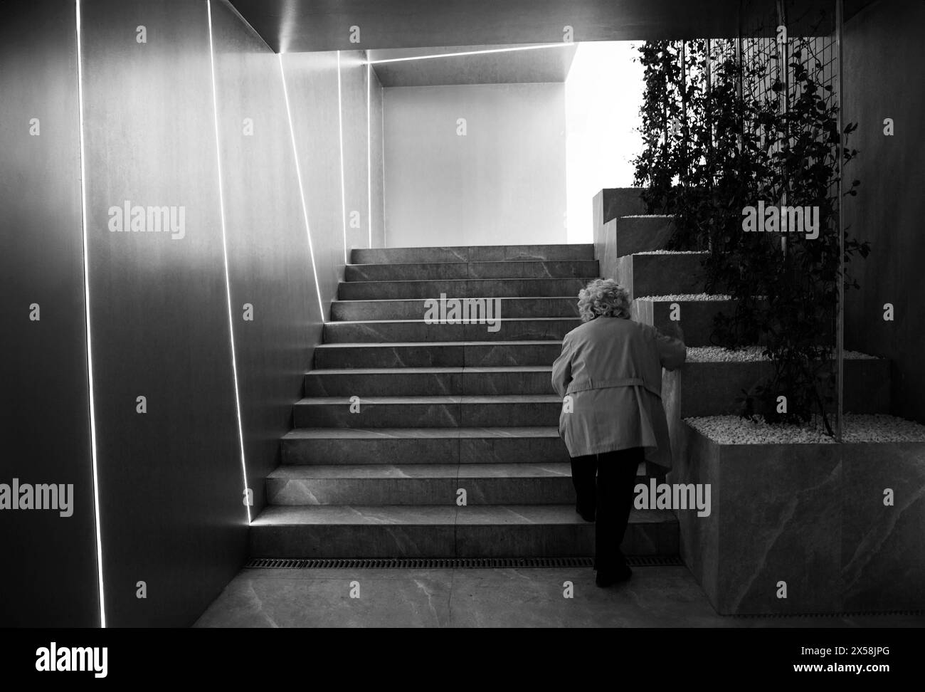 Donna anziana che sale le scale sottopassaggio pedonali Foto Stock