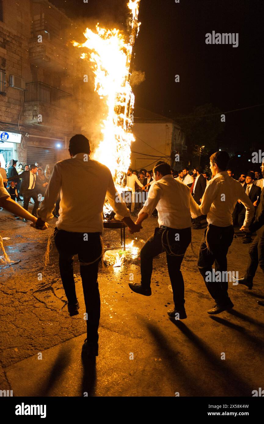 Gli ebrei ortodossi cantano e ballano per strada accanto a un falò in una tradizionale celebrazione del Lag B'Omer a Gerusalemme, Israele. Foto Stock