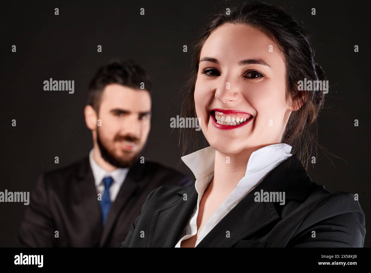 Sorridente in generale, la giovane donna in abbigliamento da lavoro cattura i riflettori, la sua collega sullo sfondo Foto Stock