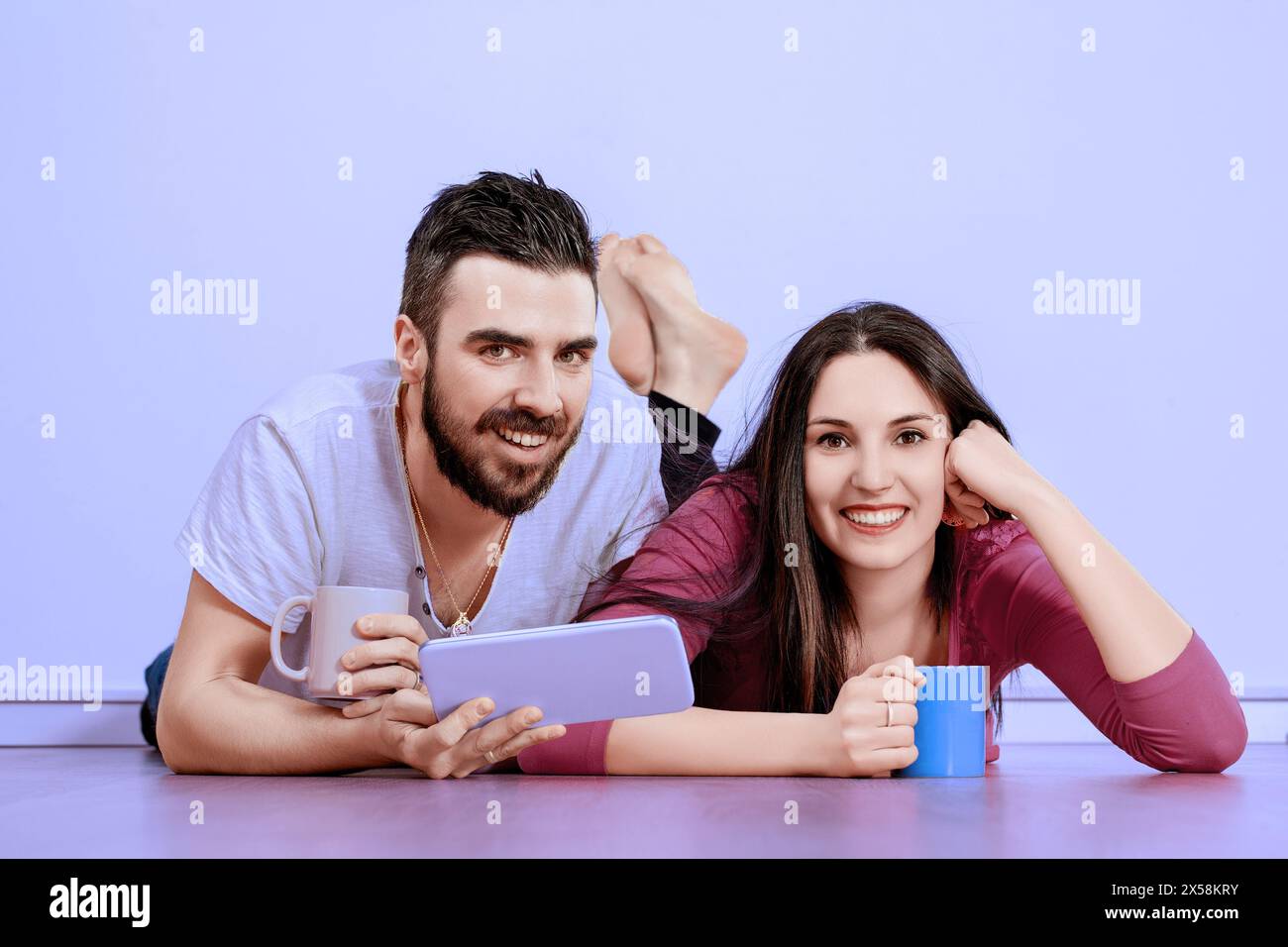 La coppia gode di un momento di relax, condividendo Risate e contenuti digitali su un tablet, la loro gioia e compagnia sono evidenti Foto Stock
