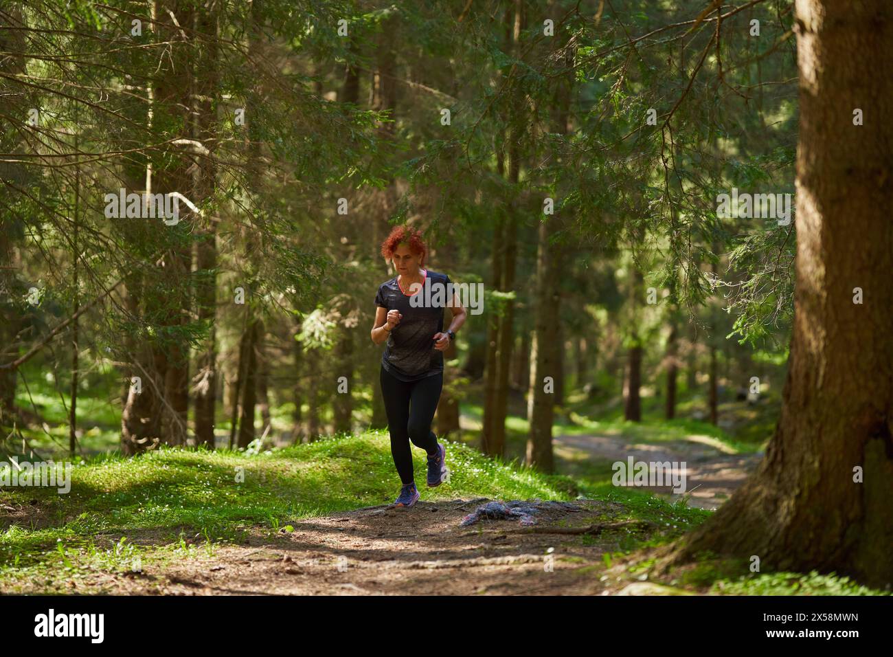Redhead Woman trail runner si sta allenando nella foresta correndo in salita Foto Stock