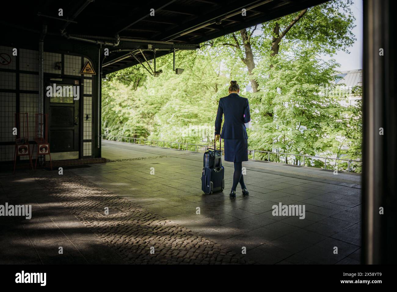 Symbolfoto zum Thema berufstaetige Frauen. Eine Frau im Business outfit steht mit einem Reisekoffer un einem Bahnsteig und wartet auf den Zug. Berlino, Foto Stock