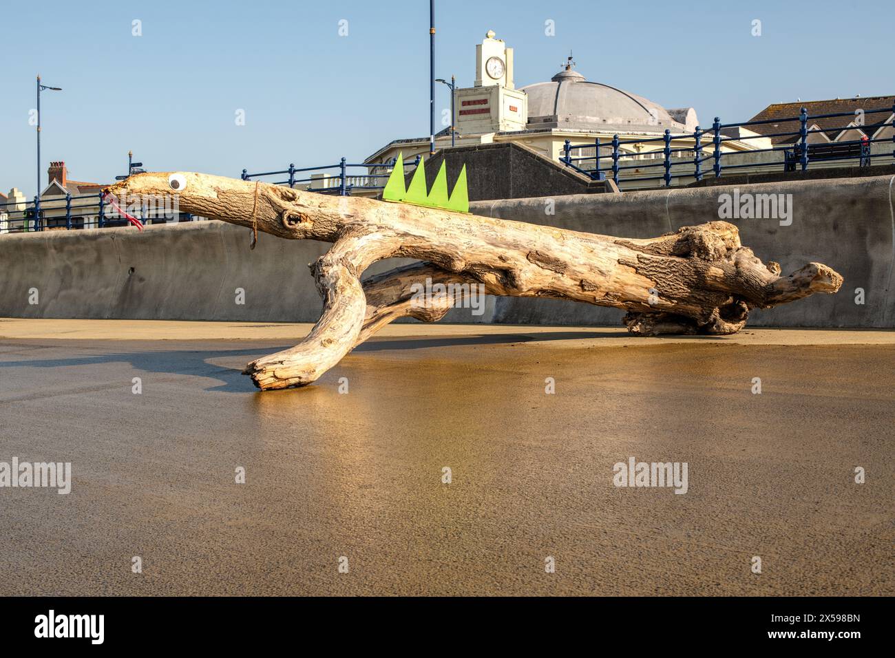 Un ceppo d'albero lavato sul lungomare di Porthcawl è stato decorato come una lucertola. Foto Stock